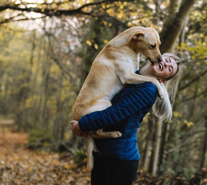 woman-carrying-dog-while-standing-in-the-middle-of-the-1612861